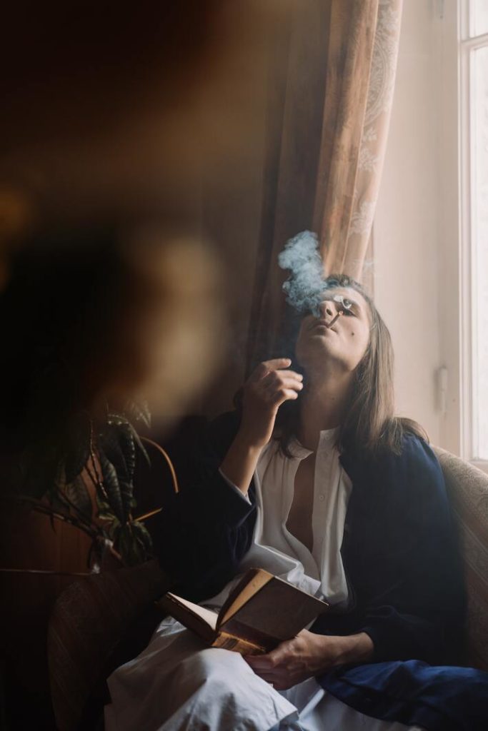 person smoking cannabis flower and reading a book for relaxation