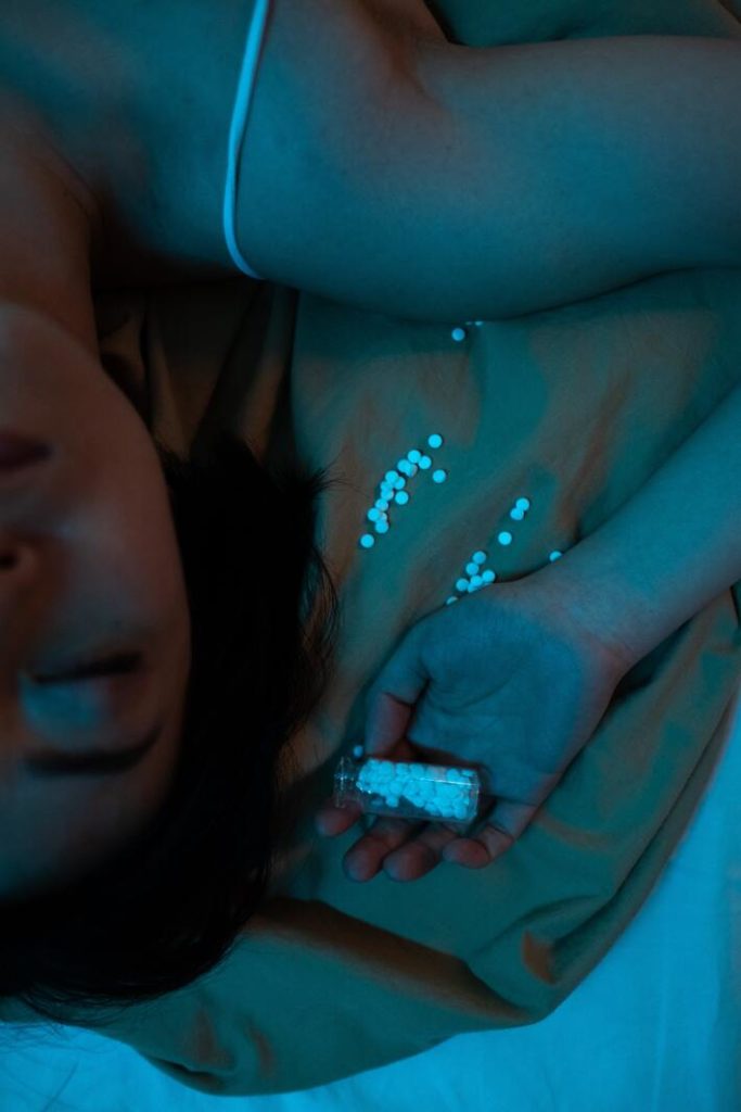woman laying next to medicinal pills
