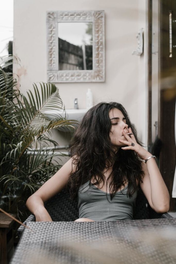 woman smoking marijuana cannabis joint outside balcony