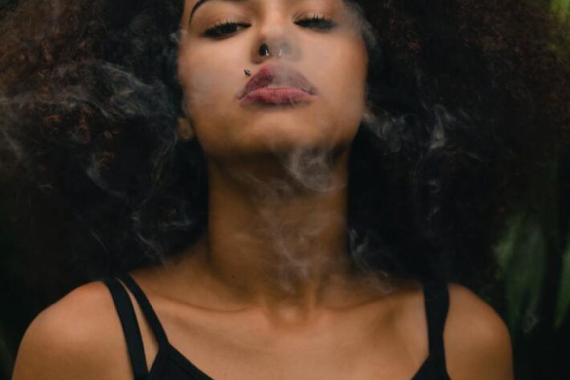 woman with cannabis smoke near face